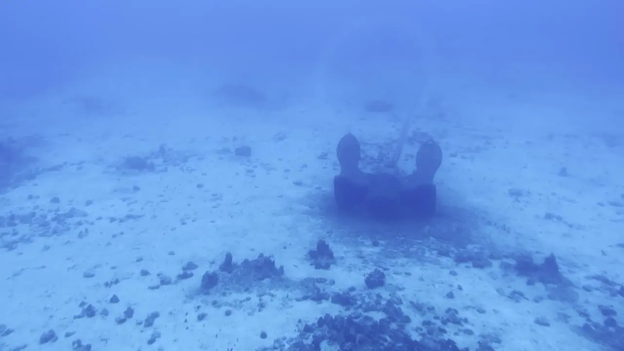 Cinematic wide dolly shot through a submarine porthole of a ship anchor on the ocean floor off the coast of the Big Island of Hawai'i