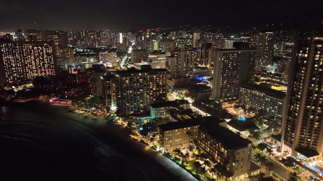 30 fps night aerial drone footage of waikiki strip traffic cars city lights palm trees in honolulu hawaii skyline