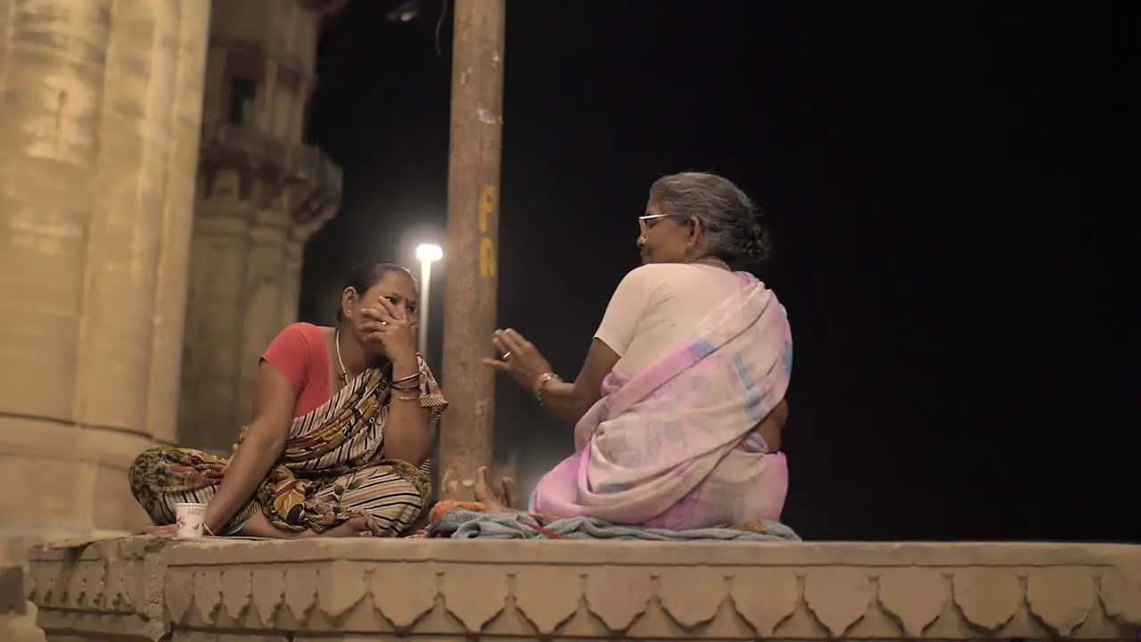 Two Ladies Sitting and Talking at Night