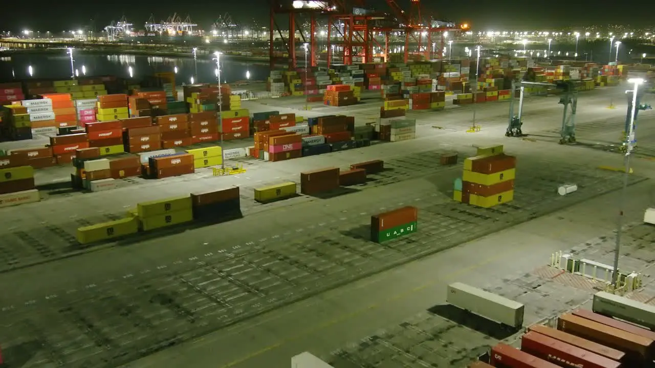 Aerial flyby over shipping containers at Long Beach shipping port | Night time | Ocean in background