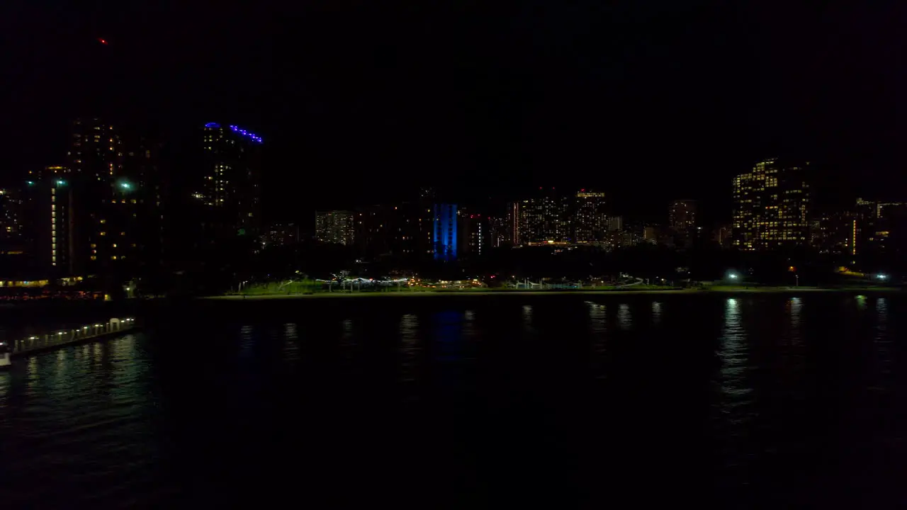 Left to right aerial view of coastline along Honolulu Hawaii at night