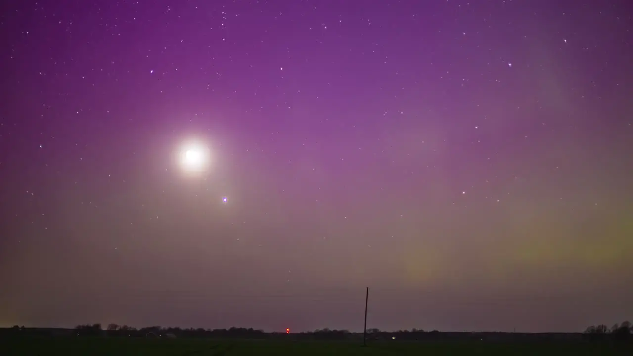 Moon stars and the aurora borealis glow in the misty nighttime sky time lapse