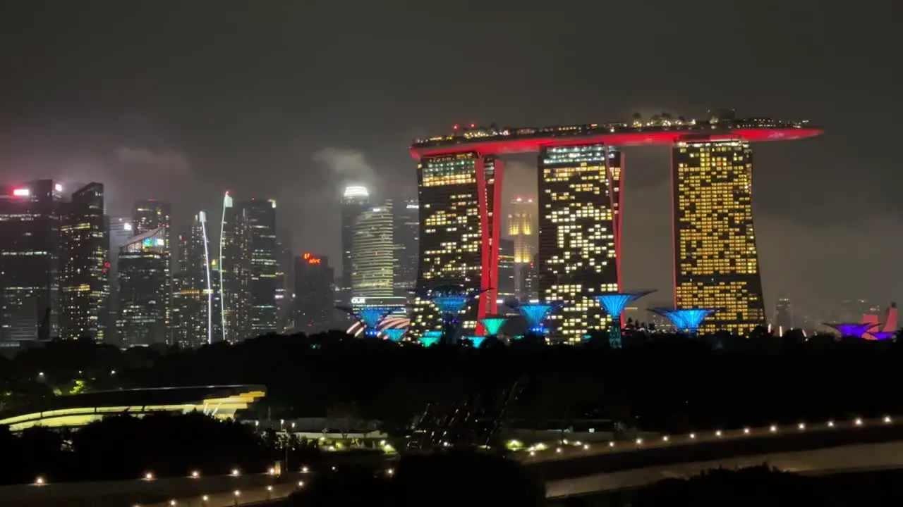 Nighttime footage from Singapore Harbor featuring Marina Bay Sands Gardens by the Bay and Avatar-like trees with Singapore's skyline on the left