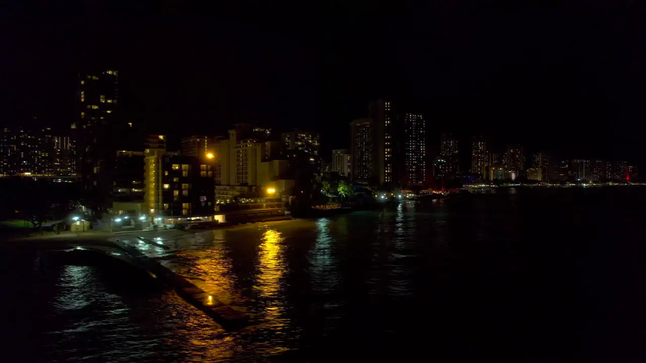 South to Southeast coastline of Honolulu Hawaii cityscape reveal of aerial view from left to right at night