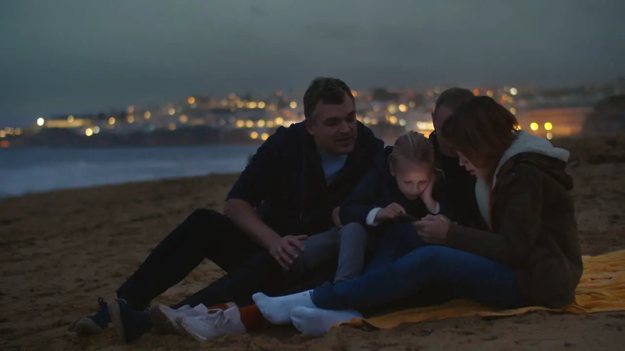 Family watching phone on ocean shore