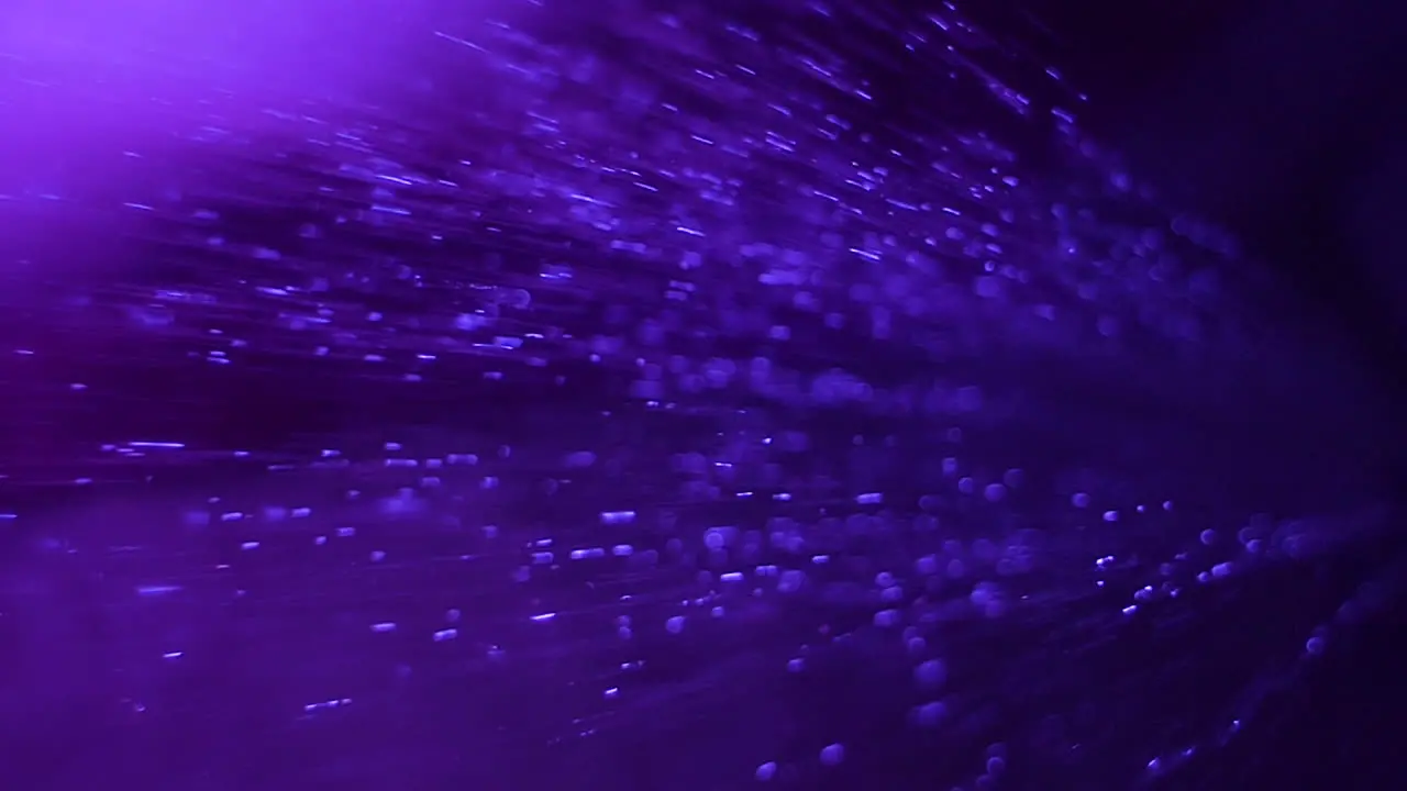 A close up of rain softly hitting the ground with a soothing purple background