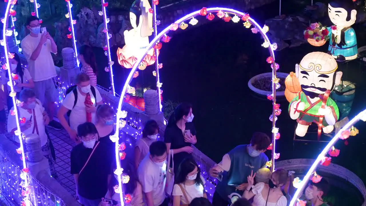 Chinese visitors walk through a bridge decorated with lights as they take selfies and enjoy a nighttime lantern show at the Wong Tai Sin temple during the Mid-Autumn Festival