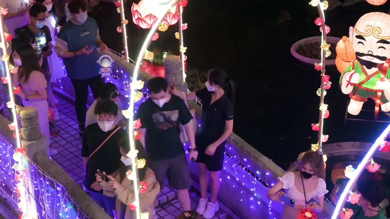 Chinese visitors walk through a bridge decorated with lights as they enjoy a nighttime lantern show at the Wong Tai Sin temple during the Mid-Autumn Festival