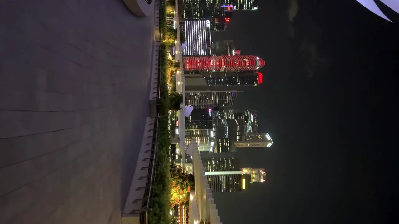 Mesmerizing vertical footage captures a nocturnal stroll around Marina Bay Sands where luminous skyscrapers adorn the dazzling cityscape creating an awe-inspiring spectacle