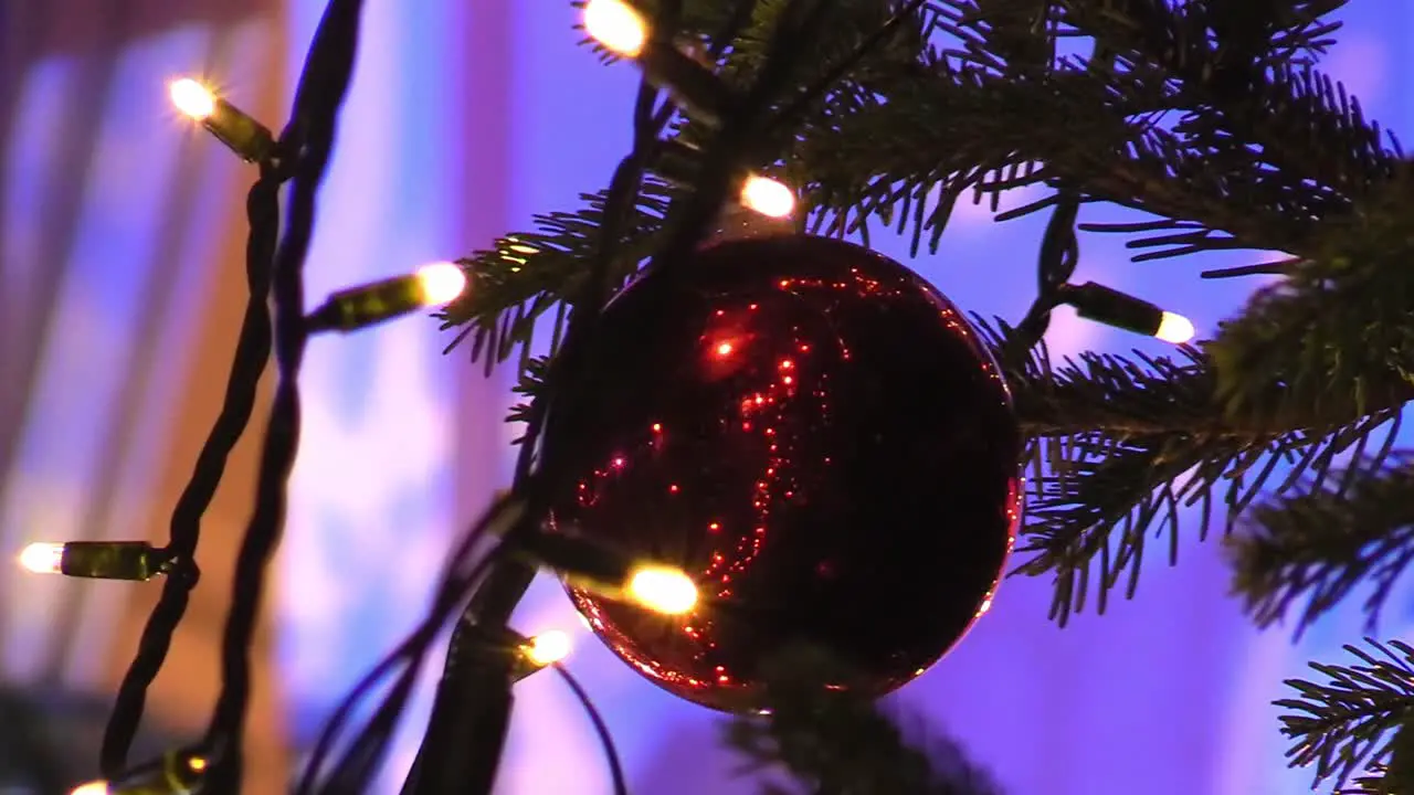 Still shot of close up of a Christmas ball on a tree The Mansion House with lights in the background