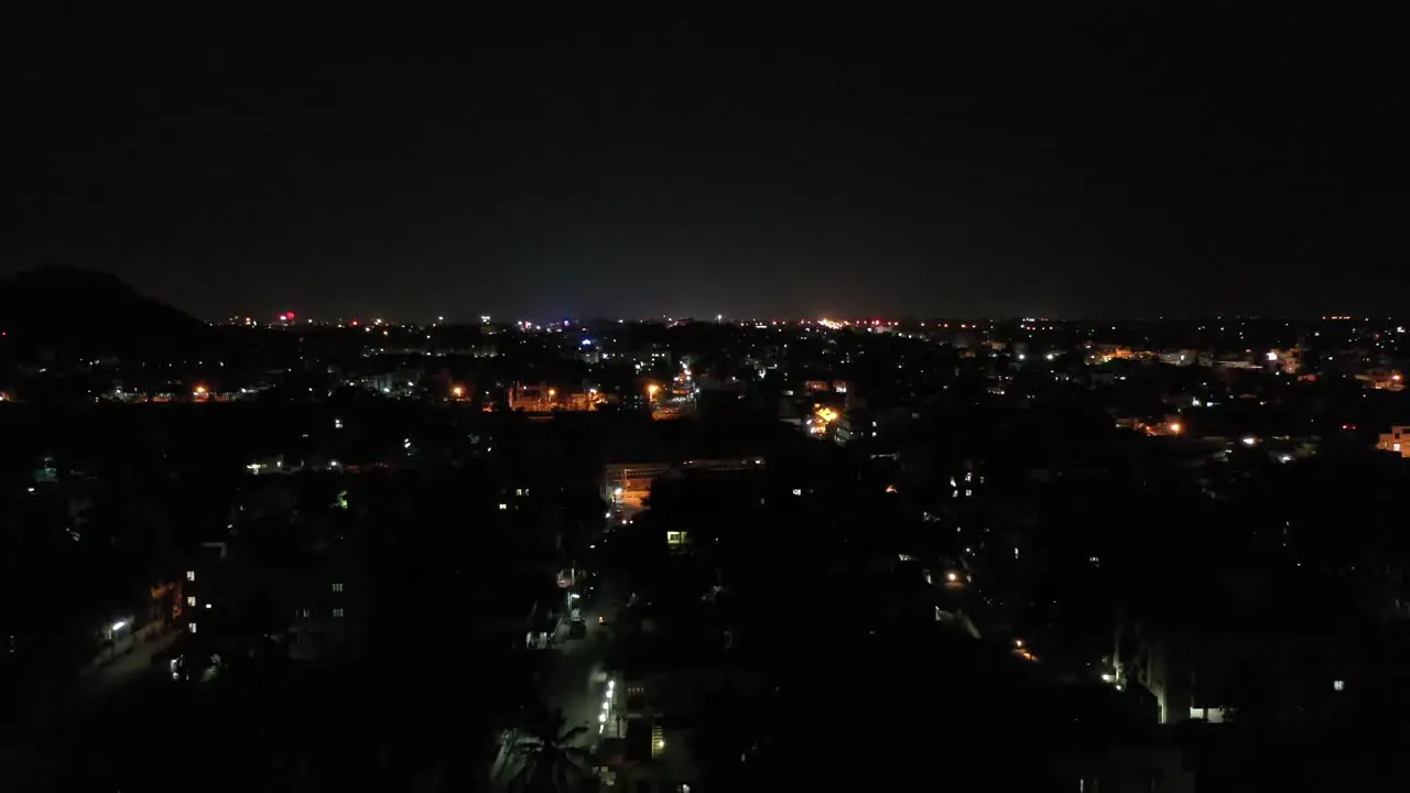 Drone video moving in night skyline with city house lights and vehicles plying on highway