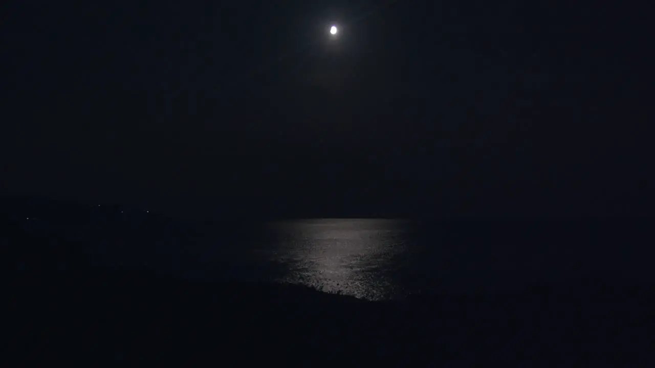 moon and moonlight reflecting over sea at night extreme long shoot