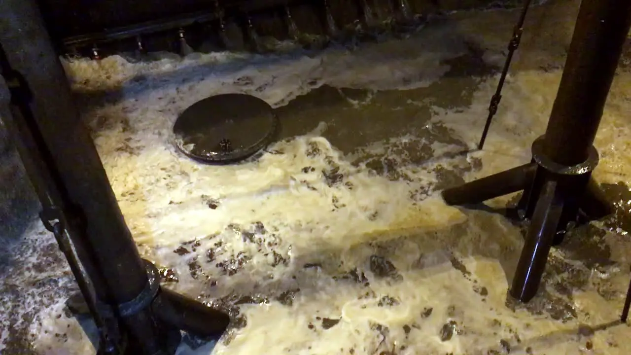 Slow motion shot of water willing a dredge hopper during nightime