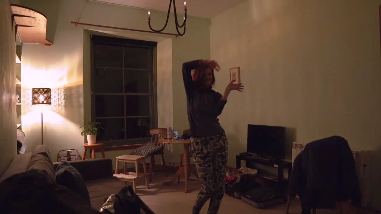 Girl dancing in the living room with soft warm light at night time