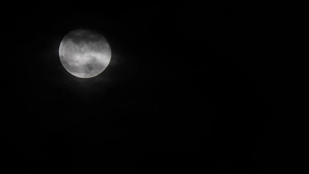 Full moon shining in a dark night sky Left