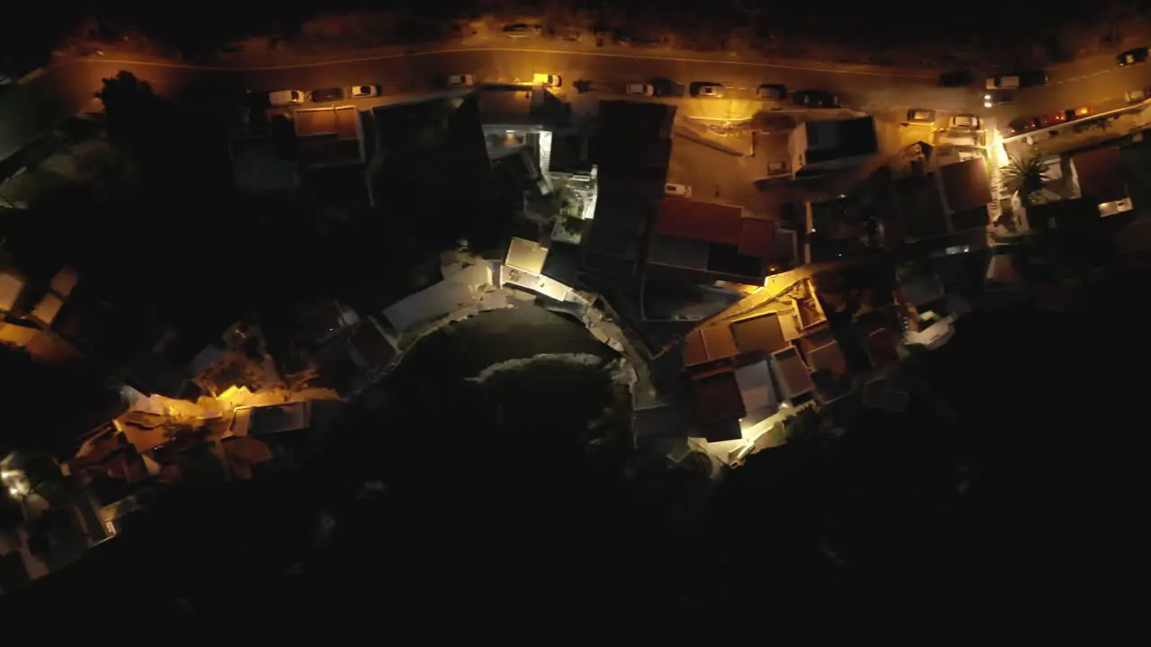 Mesmerizing overhead view of a charming coastal fisherman village at night adorned with beautiful street lights