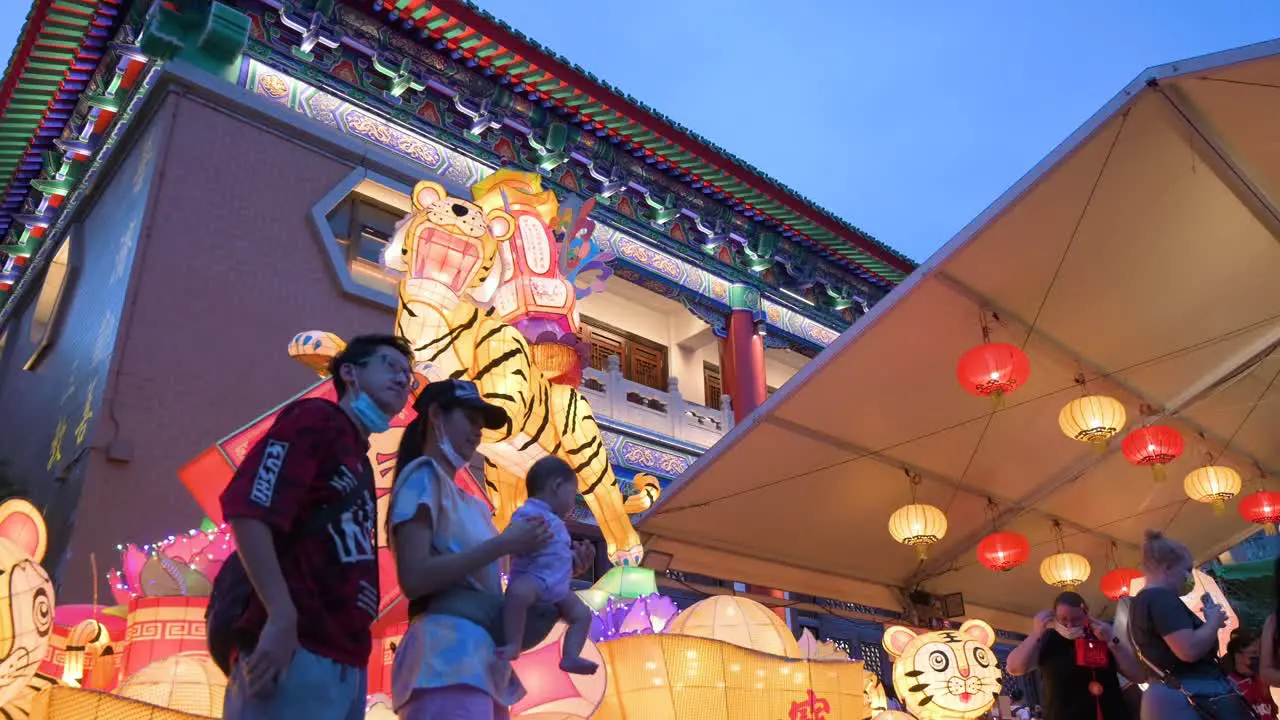 A family poses for a photo in front of a tiger theme lantern and part of a lantern show which symbolizes prosperity and good fortune at the Wong Tai Sin temple during the Mid-Autumn Festival