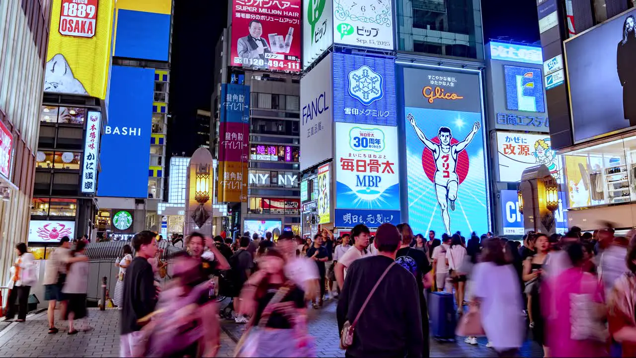 Night Time lapse of busy crowds and Illuminated signboards at Ebisubashi Bridge On The Dotonbori Canal Osaka Japan TILT