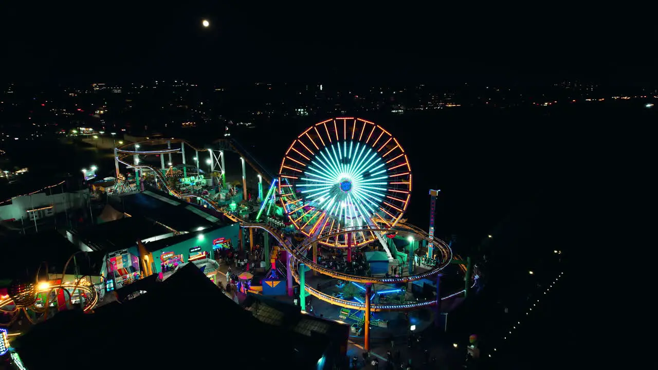 Nighttime orbital drone shot of santa monica pier and ferris wheel