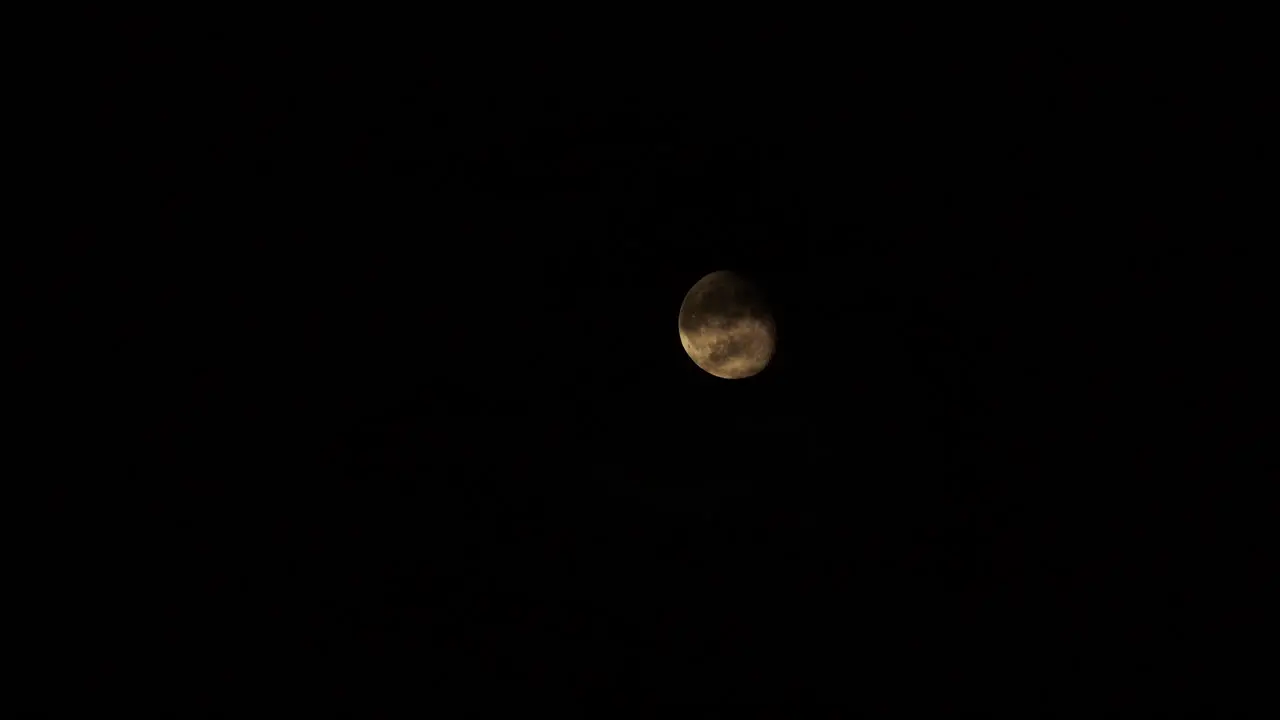 Full Moon comes out behind clouds in dark night sky