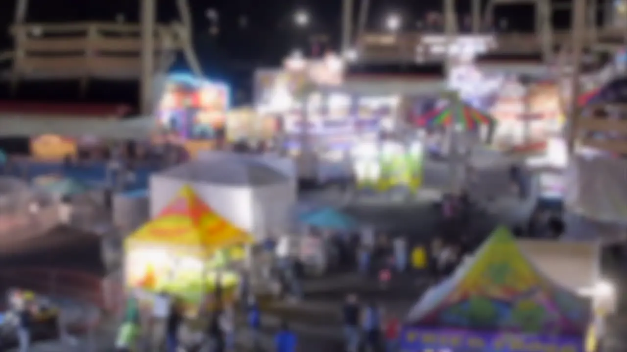 Blurry bokeh state fair carnival amusement park at night with lights and empty gondola ride