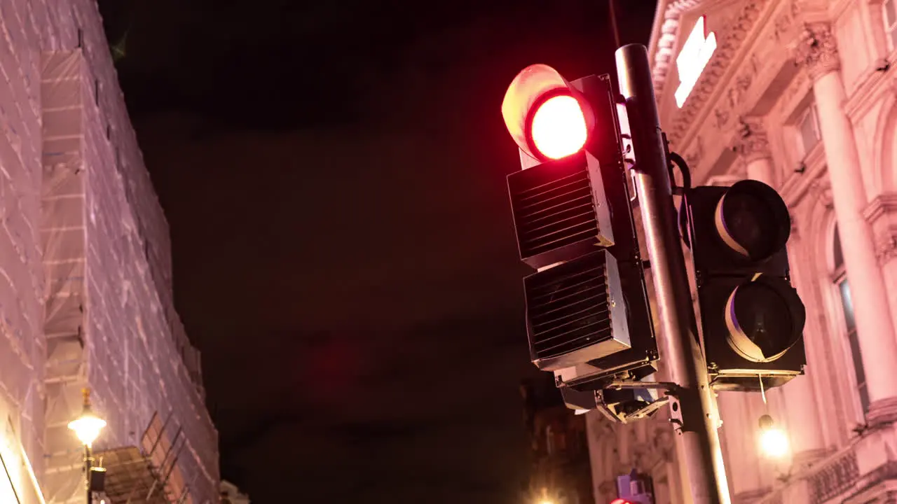 Timelapse of a busy London intersection's traffic lights working lights flash and illuminate the buildings on a busy London Street