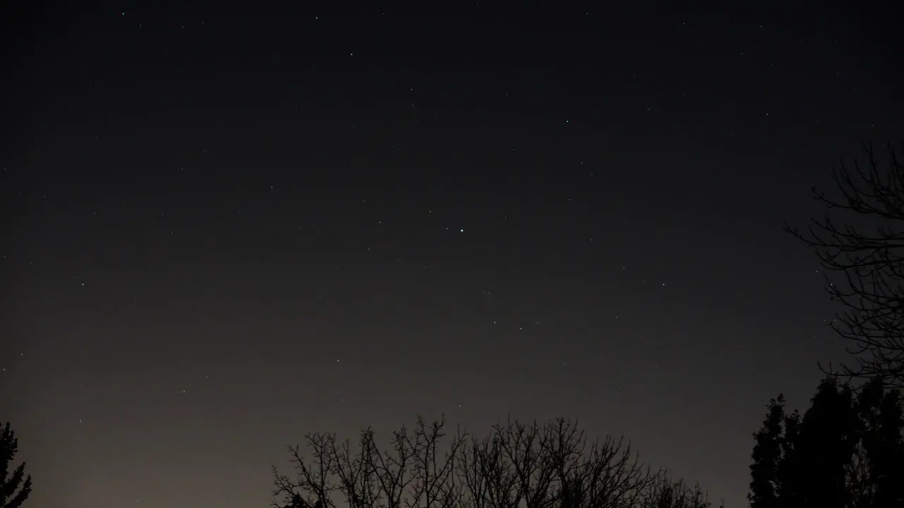 Camera tracks the star Fomalhaut in the constellation Piscis Austrinus as it moves through the sky and behind bare tree branches