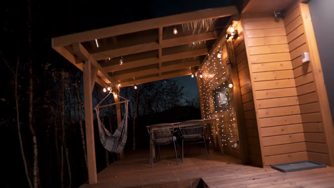 Cozy Wooden Cabin Balcony with Hammock and Warm Lights at Nighttime