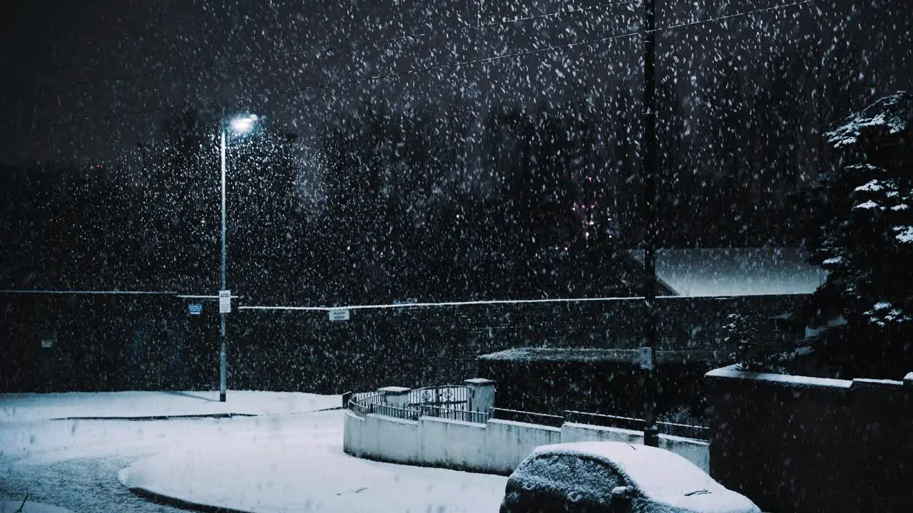 Heavy snow falling on residential street lit by streetlamp