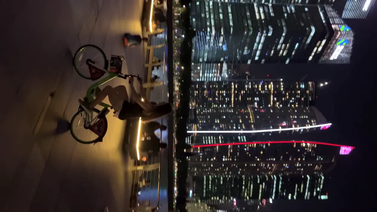 Young lady cycling through Marina Bay Singapore with the breathtaking Marina Bay Sands and skyscrappers in the background at night showcasing stunning architecture and views