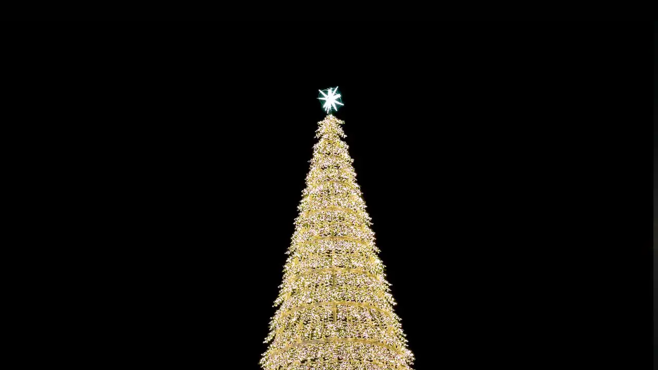 An illuminated gold LED Christmas tree installation is displayed during nighttime during the Christmas festivities