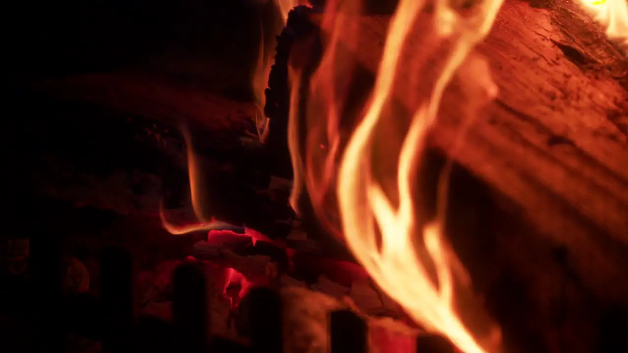 Glowing hot flames on side of wooden log in fireplace orange heat