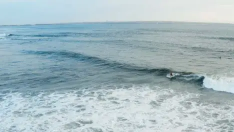 Drone Shot Following a Surfer Riding Wave Off Echo Beach Coast