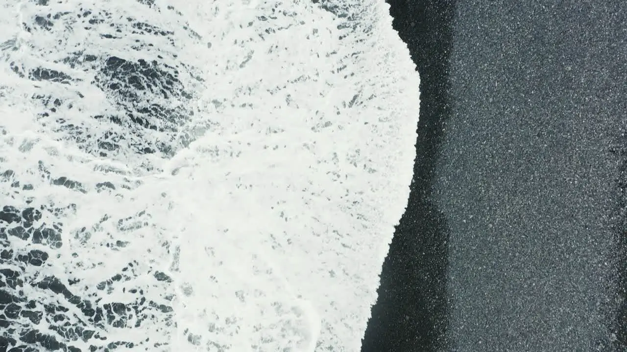 Waves breaking on black sand beach Reynisfjara in Iceland top down