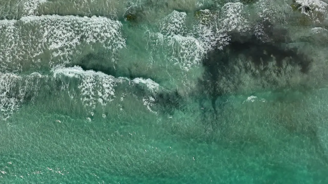 Top down view of waves hitting beach in slowmotion going forward