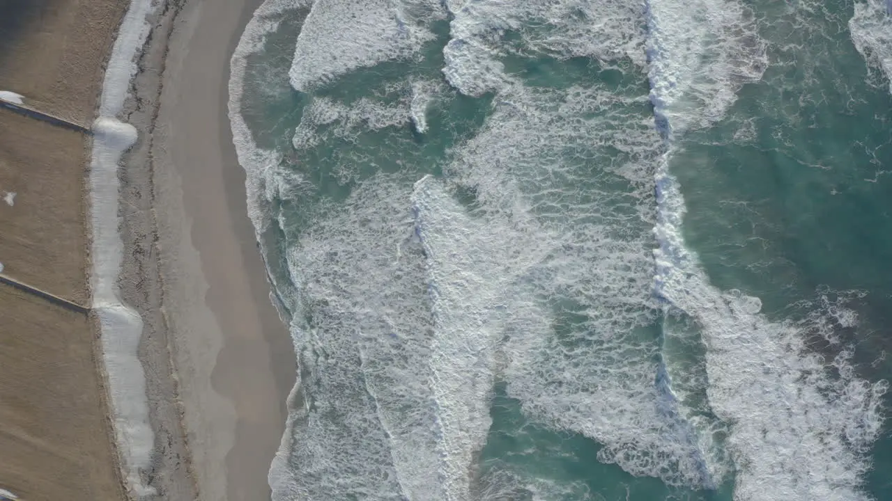 Waves crashing on Unstad beach from a bird's eye view