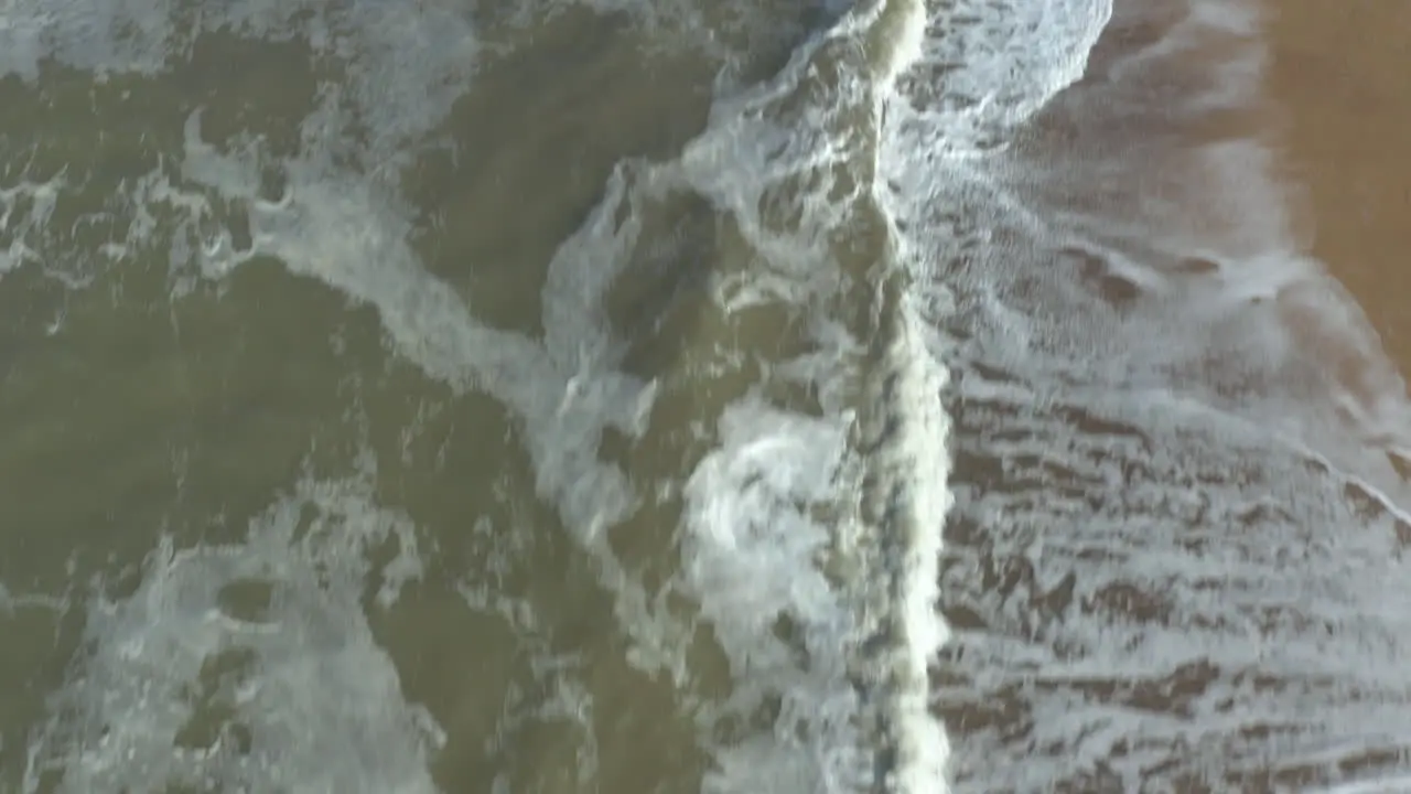 Fast aerial shot over the might sea crashing waves on a golden beach