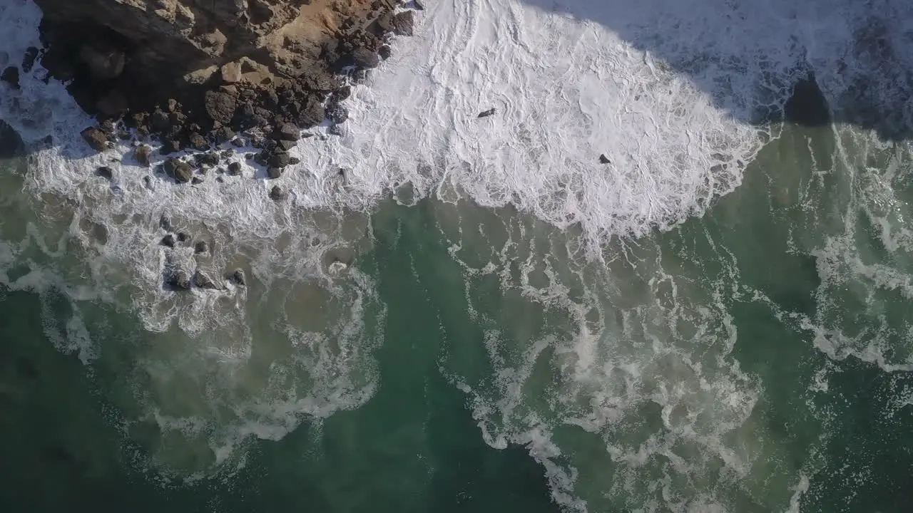 Drone top shot of sea water with corals hits by the waves