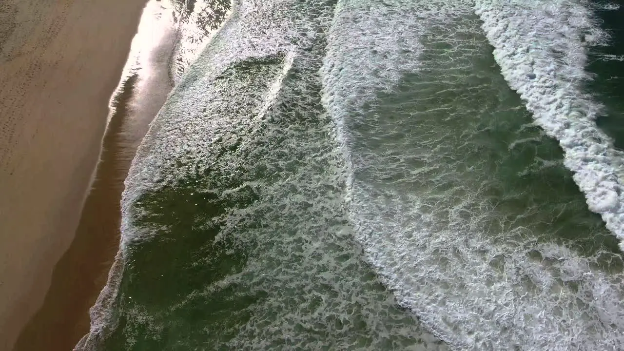 Aerial drone view of ocean with waves crashing and sand shot in 4k high resolution