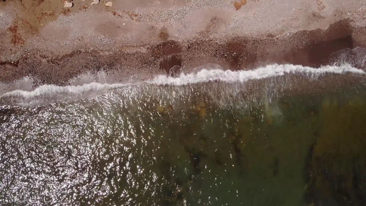 Aerial Birds Eye View Of Sea Waves Breaking On Sandy Gravel Beach In Costa del Sol