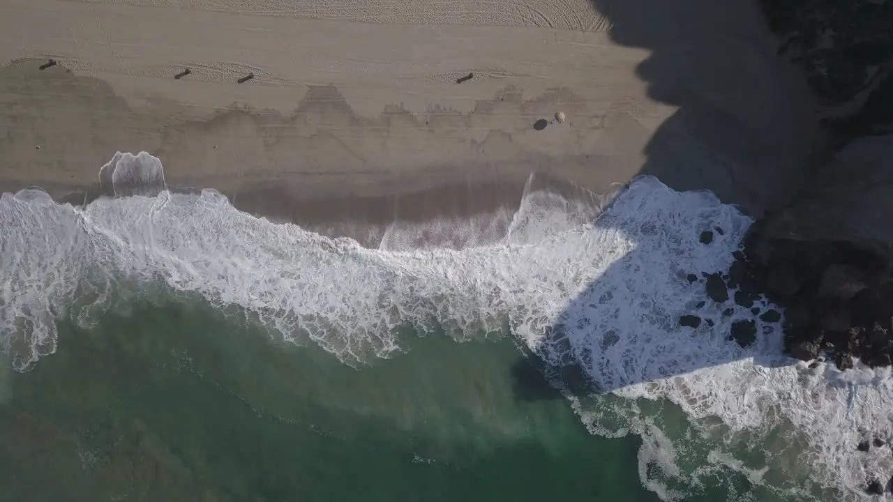 Drone head shot of sea water waves hits beachside