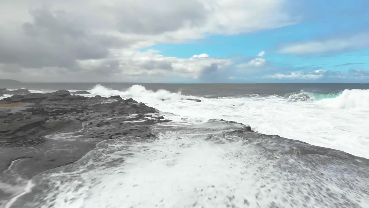 Aerial shot flying low over a rock shelf on the Victorian coast with waves pounding against the rocks