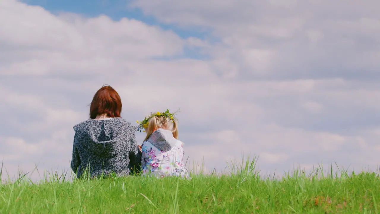 Rear View Of A Middle-Aged Woman With Her Daughter Making A Wreath Of Wild Flowers Together