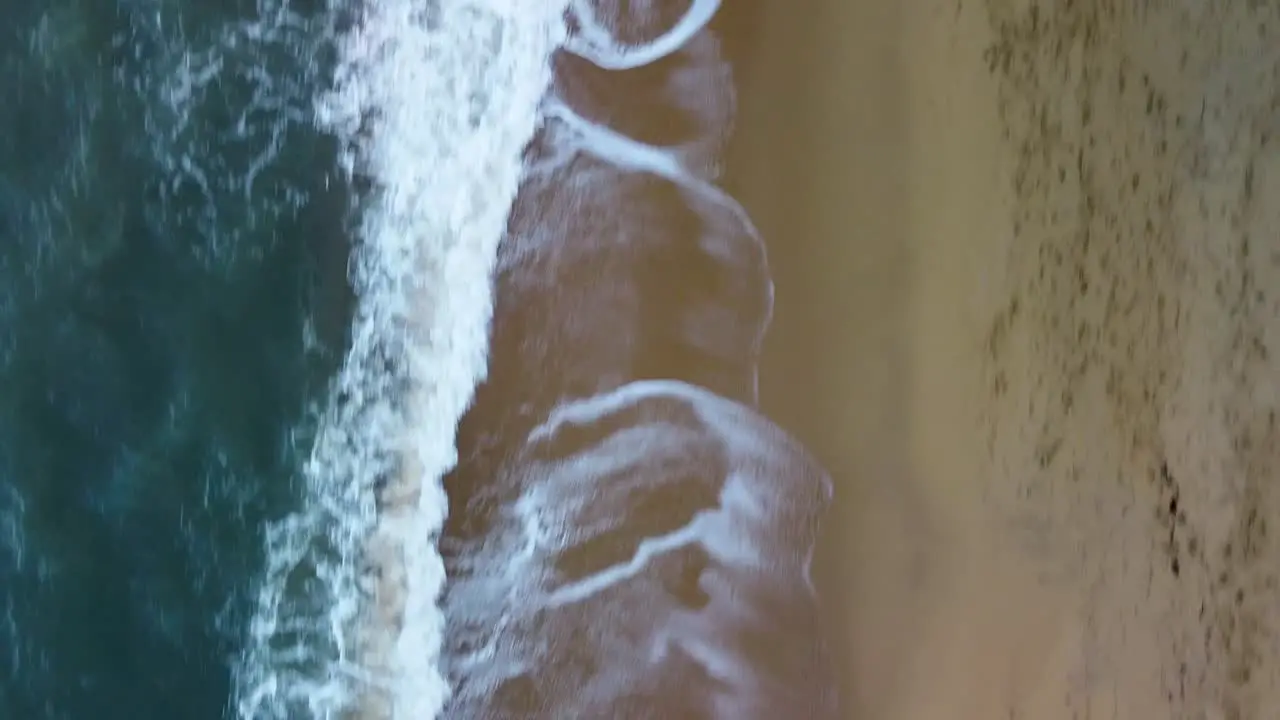 Aerial Top Down View Of Tropical Beach Foamy Ocean Waves Washing Sand