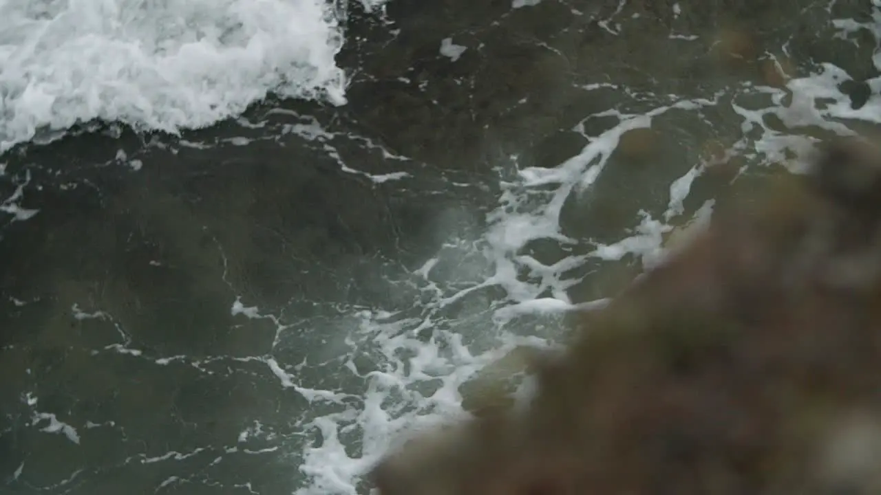 Epic wave burst of drops on foamy water with pan from down to up