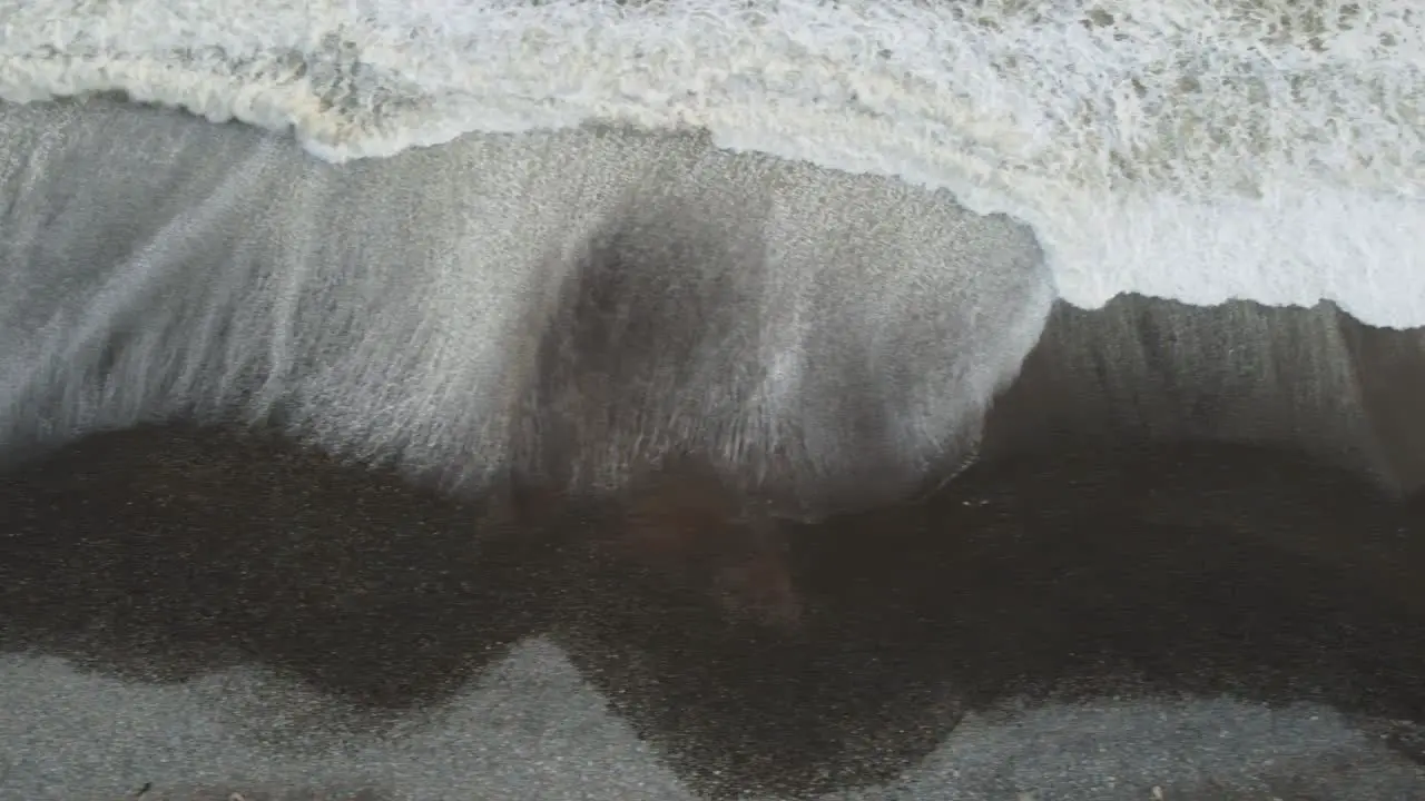 Topdown drone footage of waves on a rocky beach