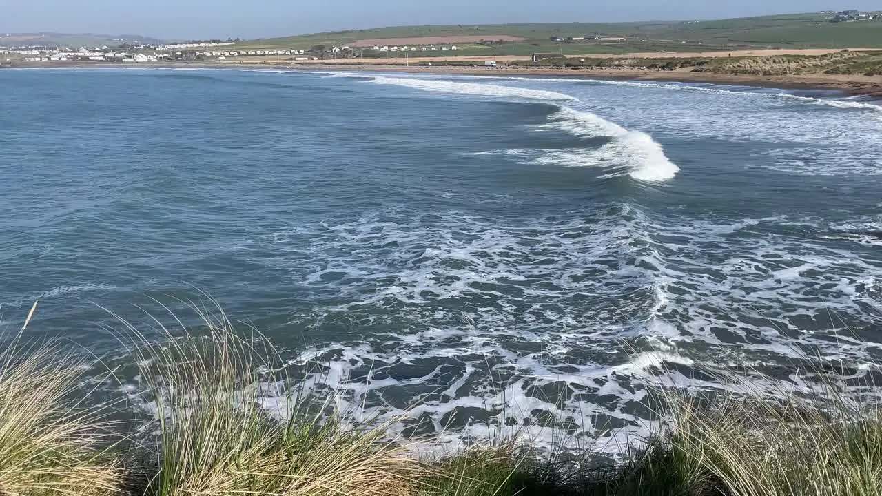 Hazy day on the Irish coast with swell creating rainbows in wave crests