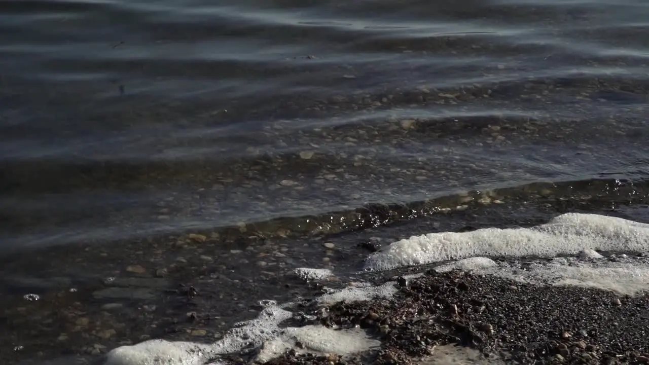 Rotating shot in slow motion of waves hitting rocks during daytime