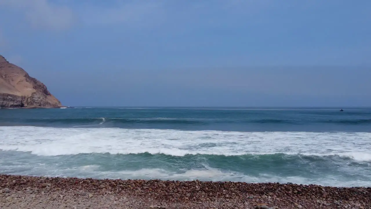 drone footage flying through two pillars in a rocky beach called "La Herradura" in Lima Peru