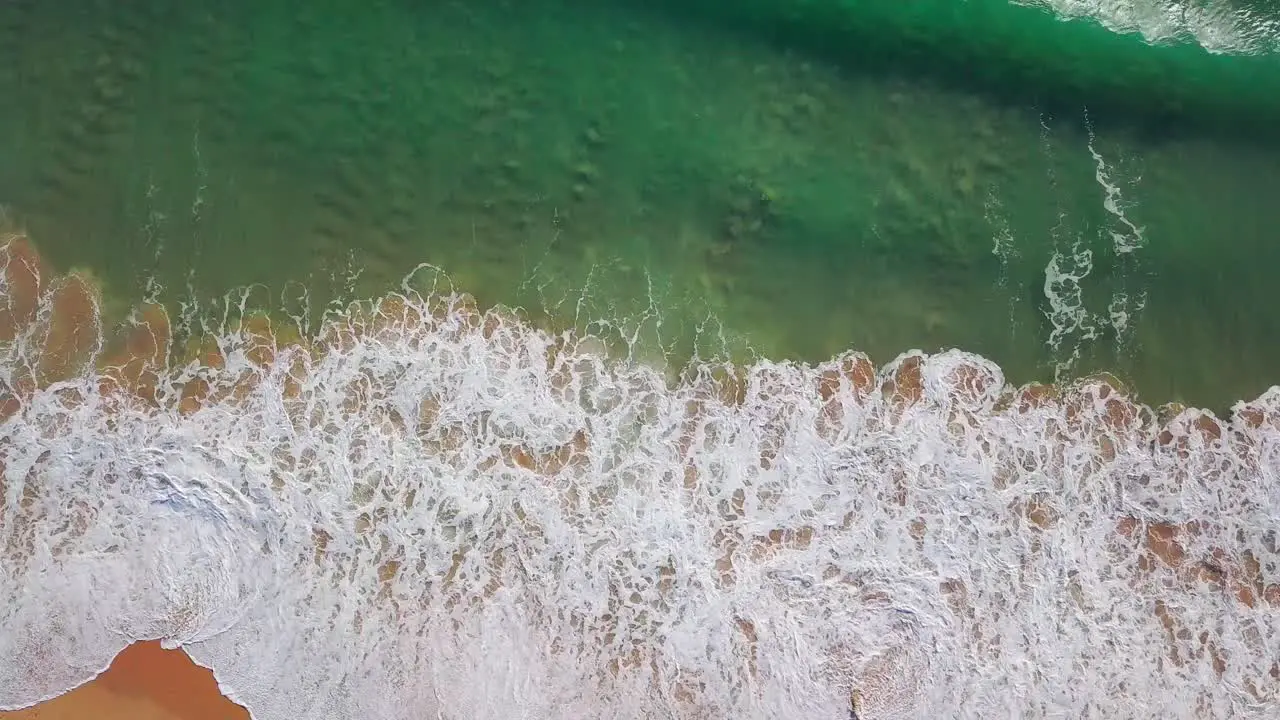 Aerial still shot of big waves crashing into a sandy beach